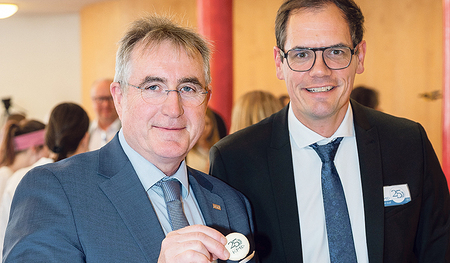 HLW-Direktor Stefan Schuhmann (re.) bietet Manfred Schörghuber von der OÖ Bildungsdirektion Jubiläumskekse an.    