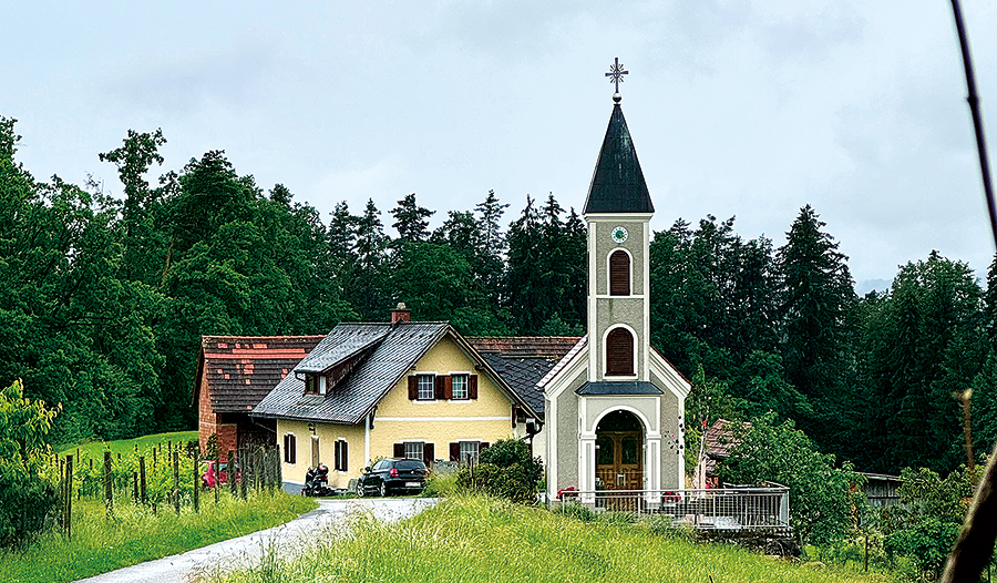 Kapelle des Marathonläufers, im Hintergrund ein Haus und Wald