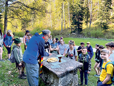 Brotbrechen. Pfarrer Christian Öhler feiert mit Kindern und Jugendlichen Eucharistie.