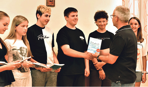 Ein gutes Gefühl: Das Buch ist fertig. Firmbegleiter Stefan Manahl übergibt jedem seiner Firmlinge ein druckfrisches Exemplar.    