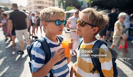 Kids tourists sightseeing town in Majorca. Two young brothers savor the freshly squeezed orange juice in a charming Spanish town. The juice has been prepared at a farmers' market stand, with locally grown oranges. Shot with Nikon D850