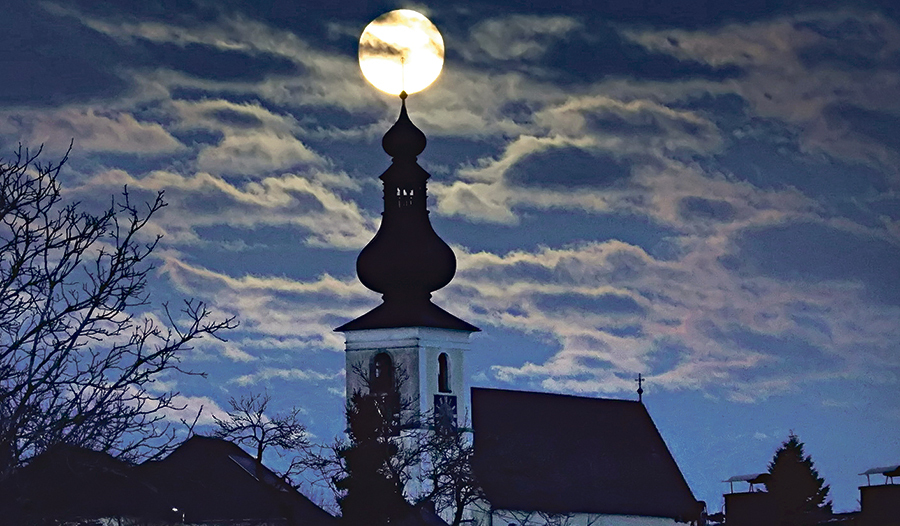 Der Vollmond scheint im Turmkreuz der Kaplaneikirche zu ruhen.  