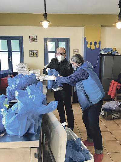 Bischof Hermann Glettler hilft auf Lesbos der Grazer Menschenrechtsaktivistin Doro Blancke beim Verpacken von Essensrationen.