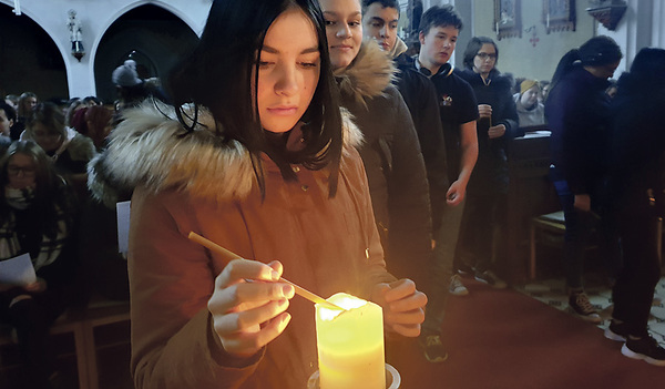 Eine Schülerin entzündet bei der Rorate in Kleinraming eine Kerze.    