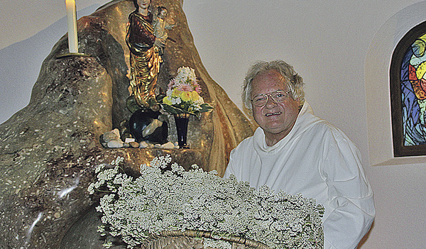 Pater Johannes Pausch bringt Schafgarben vor die Marienstatue in der Kirche des Klosters Gut Aich.