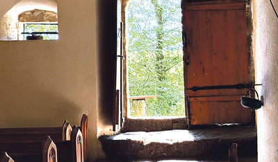 Zwischen Bäumen versteckt sich das ursprünglich romanische Gotteshaus.