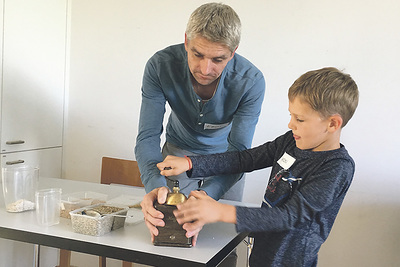 Gemeinsam die Kerze verzieren (oben) und im Stationenbetrieb Materialien passend zum Kirchenfest begreifen: hier Moos und Rinde für die Krippengestaltung (Mitte), Bohnen reiben und den Duft genießen (unten).