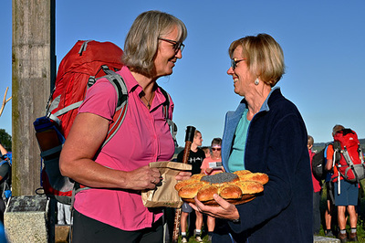 Paula Wintereder (Vorsitzende der kfb oö) gibt Margit Schmidinger Brot und Wein zur Stärkung mit. Die kfb oö unterstützt die Rompilgerin.