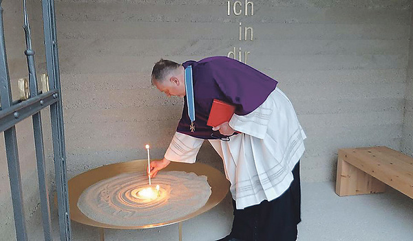 Pfarrer Wolfgang Schnölzer entzündet eine Kerze in der neuen Gedenkstätte.  