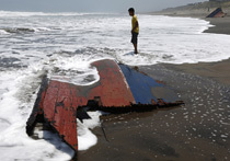 A youth stands near a piece of wreckage of a boat which sank off the Indonesian coast, at Agrabinta beach on the outskirts of Sukabumi, Indonesia's  West Java province September 28, 2013. The boat carrying migrants to Australia sank off the Indonesia