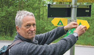 Das Grüne Dreieck mit Kreuz und rot-weißem Schachbrettmuster ist das Logo des Benediktwegs. Reinhard Niederkrottenthaller hat den Weg durch OÖ geplant und die Markierungen angebracht.  