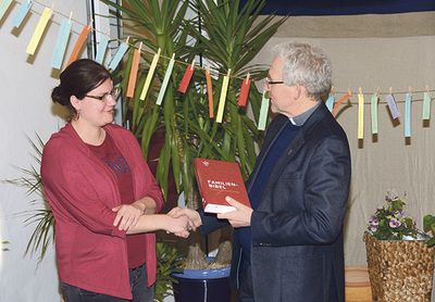 Bischofsvikar Johann Hintermaier überreichte Anja Preinfalk aus Laakirchen als 850.000. Besucherin der Ausstellung „Expedition Bibel“ die neue Familienbibel.   