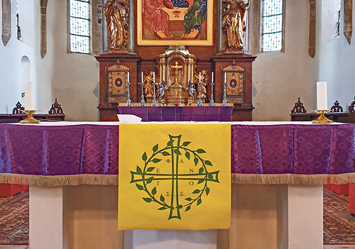 Blick in den Altarraum der Pfarrkirche Obernberg, mit einer Textilikone nach der Darstellung von Andrej Rublëv aus dem Jahr 1411 und dem Logo der von Pfarrer Wiesinger initiierten Stephanusrunde (vorne)    