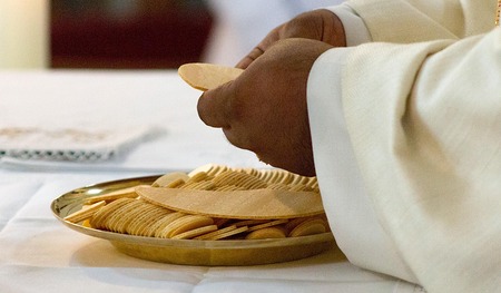 Abbildung: Priester der die Hostie zerbricht.