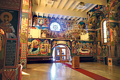 Blick auf die Rückwand der serbisch-orthodoxen Kirche in Linz. Rechts vom Portal befindet sich die Darstellung der Entschlafung Mariens und links von der Tür „Maria Geburt“.  