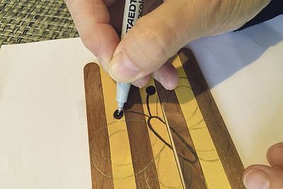 Male ein beliebiges Motiv auf der Vorderseite zunächst mit Bleistift vor. Dann ziehst du die Linien mit Filzstift nach.