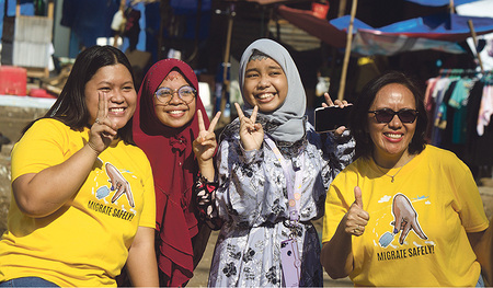 Glorie Seno (links außen) und Inorisa S. Elento (rechts außen) mit  weiteren Frauen des kfbö-Partnerinnenprojekts MMCEAI. Sie setzen sich  u. a. für sichere Arbeitsmigration ein, wie auf ihren gelben T-Shirts zu lesen ist („Migrate safely“ ).  