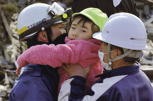Rescue workers hold a girl they rescued from a building after a tsunami and earthquake in Kesennuma City, Miyagi Prefecture, in northeastern Japan March 12, 2011. Japan confronted devastation along its northeastern coast on Saturday, with fires ragin