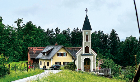 Kapelle des Marathonläufers, im Hintergrund ein Haus und Wald