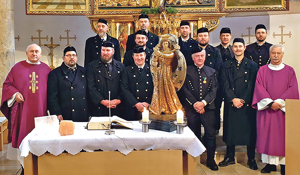 Eine Abordnung von Bergleuten in ihrer traditionellen Uniform; auf dem Altar stehen neben einer Barbarastatue auch Salzsteine.    