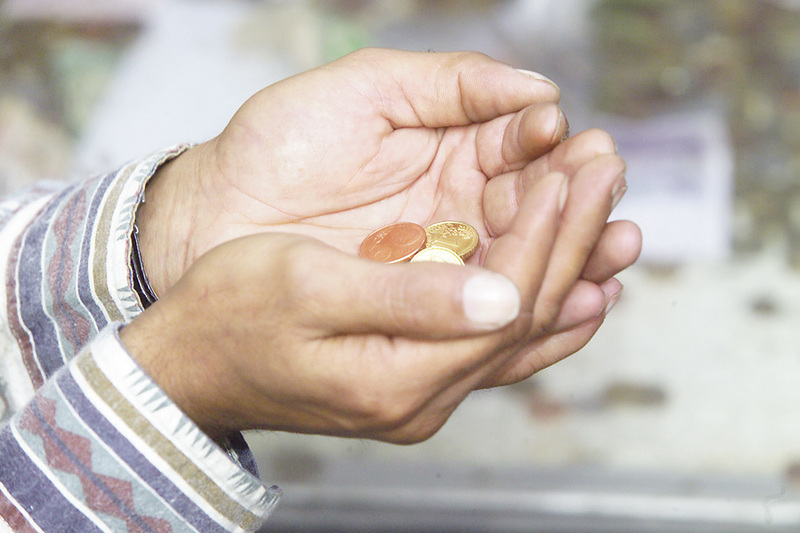 Ein Bettler hält einige kleine Münzen in seinen  geöffneten Händen.  