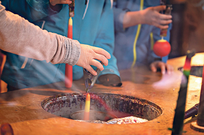 Der Docht wird immer wieder in Wachs getaucht. 