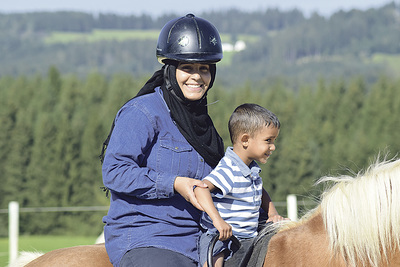 Eine Mutter mit ihrem Sohn probiert das Reiten.