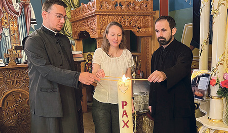Diakon Nemanja Micic (von links), Ökumene-Referentin Gudrun Becker und Priester Zoran Vrbaški entzünden die Friedenskerze in der serbisch-orthodoxen Kirche in Linz.    