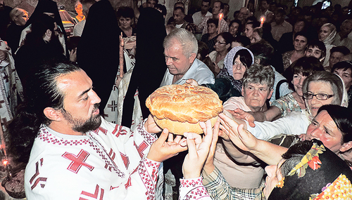 Der „Slavski Kolač“, ein Festtagskuchen, wird von dem serbisch-orthodoxen Priester und dem Volk gehalten und mit kleinen Bewegungen ­gedreht – Zeichen der Einheit und der Ewigkeit (Kloster Krupa, Kroatien).