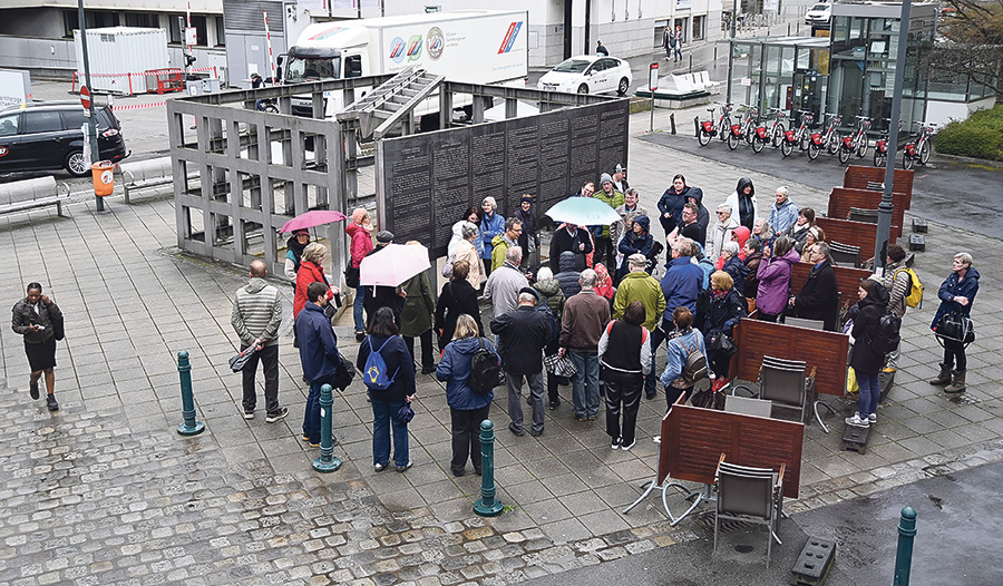 Die Stadtspaziergänger:innen vor dem Menschenrechtsbrunnen auf dem Friedensplatz 