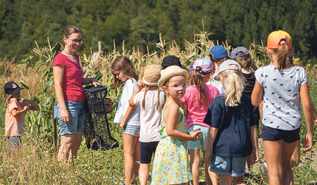 Tanja Gaßer zeigt Kindern, was auf dem Feld wächst.  