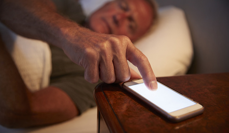 Sleepless Senior Man In Bed At Night Checking Mobile Phone