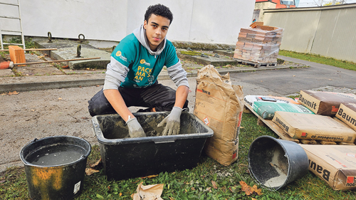Ziyad Allam beim Anrühren des Zements für die Gestaltung des Wandgrabs zum Thema Zwangsarbeit.  / KIZ/PS